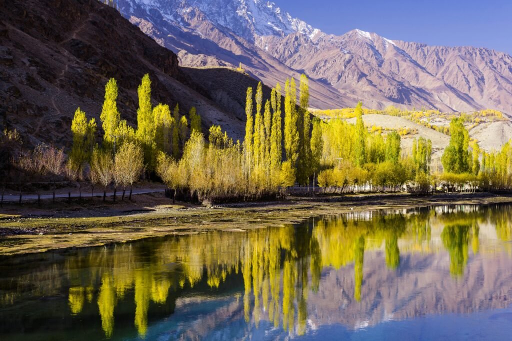 Stunning autumn scenery with vibrant trees reflected in Phander Lake, Pakistan.