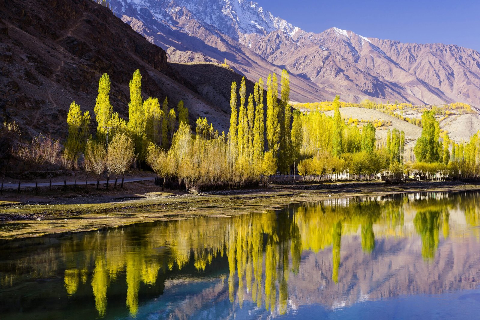Stunning autumn scenery with vibrant trees reflected in Phander Lake, Pakistan.
